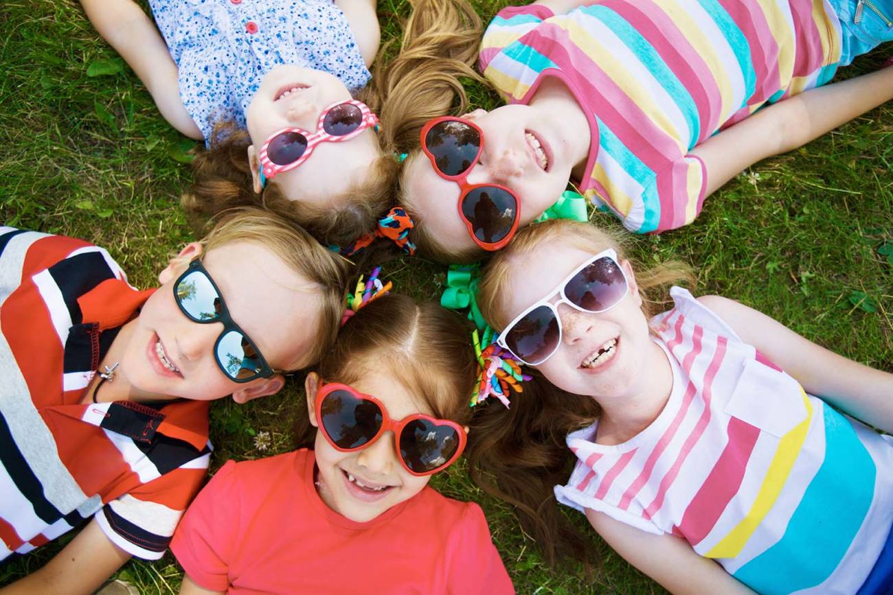 5 children wearing sunglasses laying on the grass