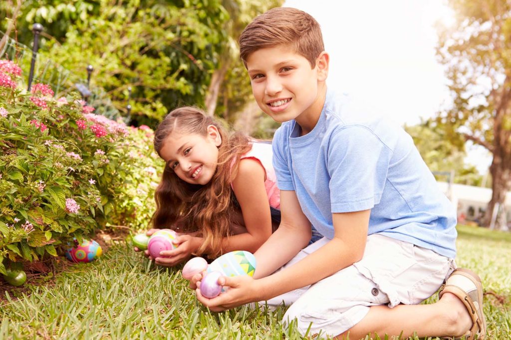 Two children holding Easter eggs in the backyard
